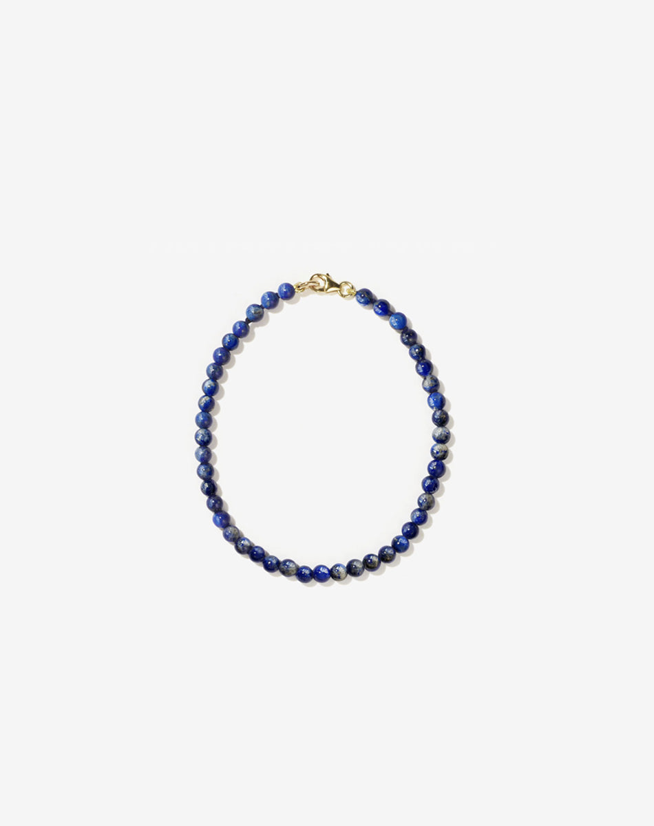 Small spherical lapis lazuli stone beads on silk thread with gold clasp bracelet